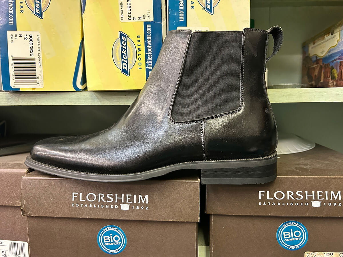 A black Florsheim leather Chelsea boot on Florsheim shoe boxes at Kornfeld's.