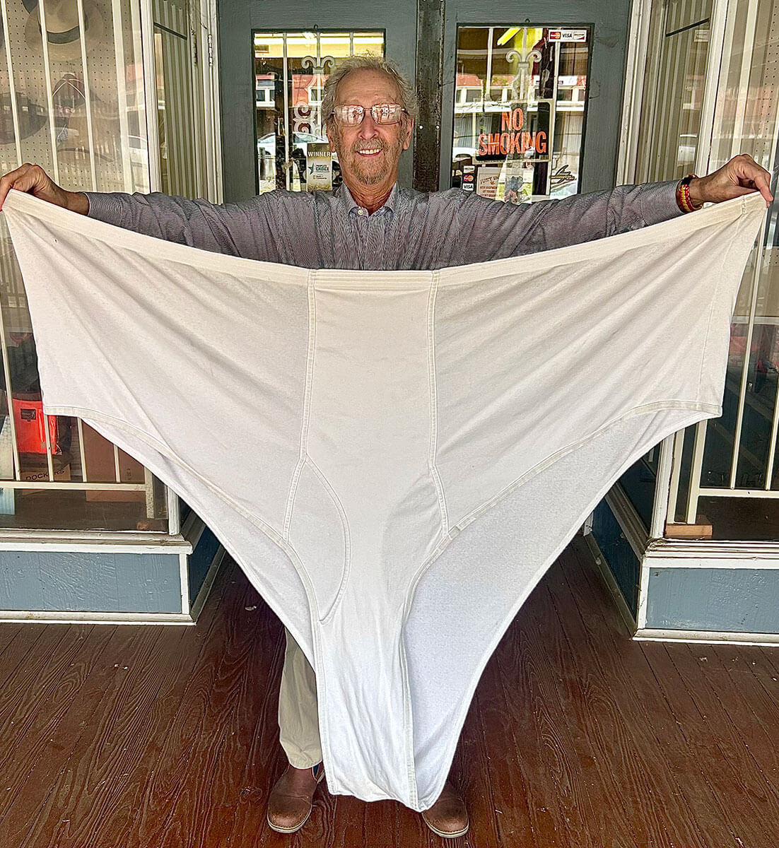 Bubba Kornfeld in front of the Kornfeld's storefront holding extra-large Big & Tall underwear to show the scale of sizes carried.