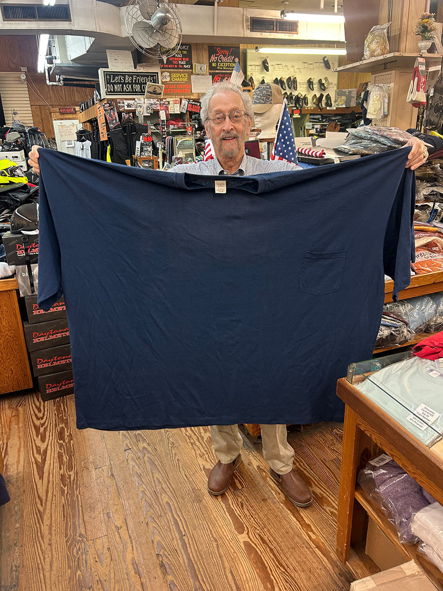 Bubba Kornfeld holding up an oversized navy Big & Tall t-shirt to show its scale.