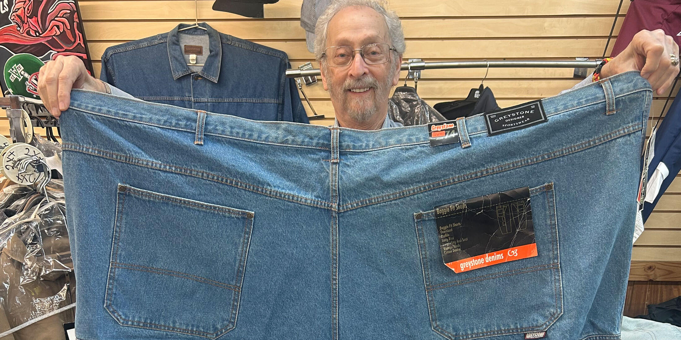 Bubba Kornfeld holding up an oversized pair of Big & Tall denim shorts inside Kornfeld's Department Store.