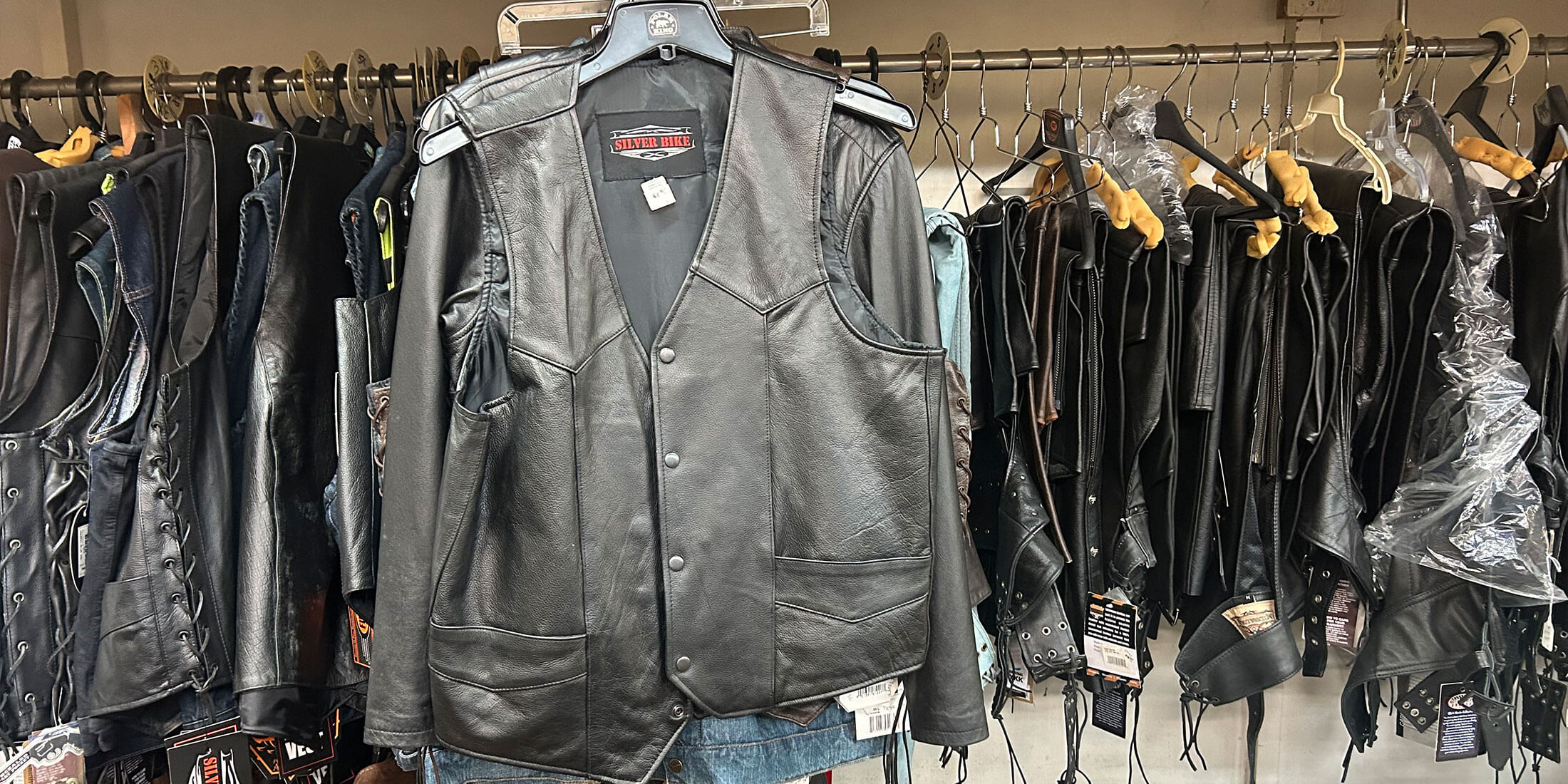 A Silver Bike leather motorcycle vest displayed in front of racks of leather vests and jackets at Kornfeld's.