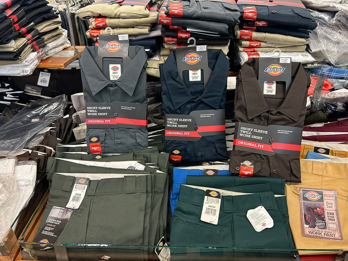 Folded Dickies double-knee work pants in green, blue and tan at Kornfeld's.