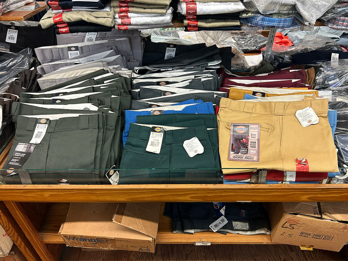 Stacks of folded Dickies work pants in khaki, navy and black at Kornfeld's.